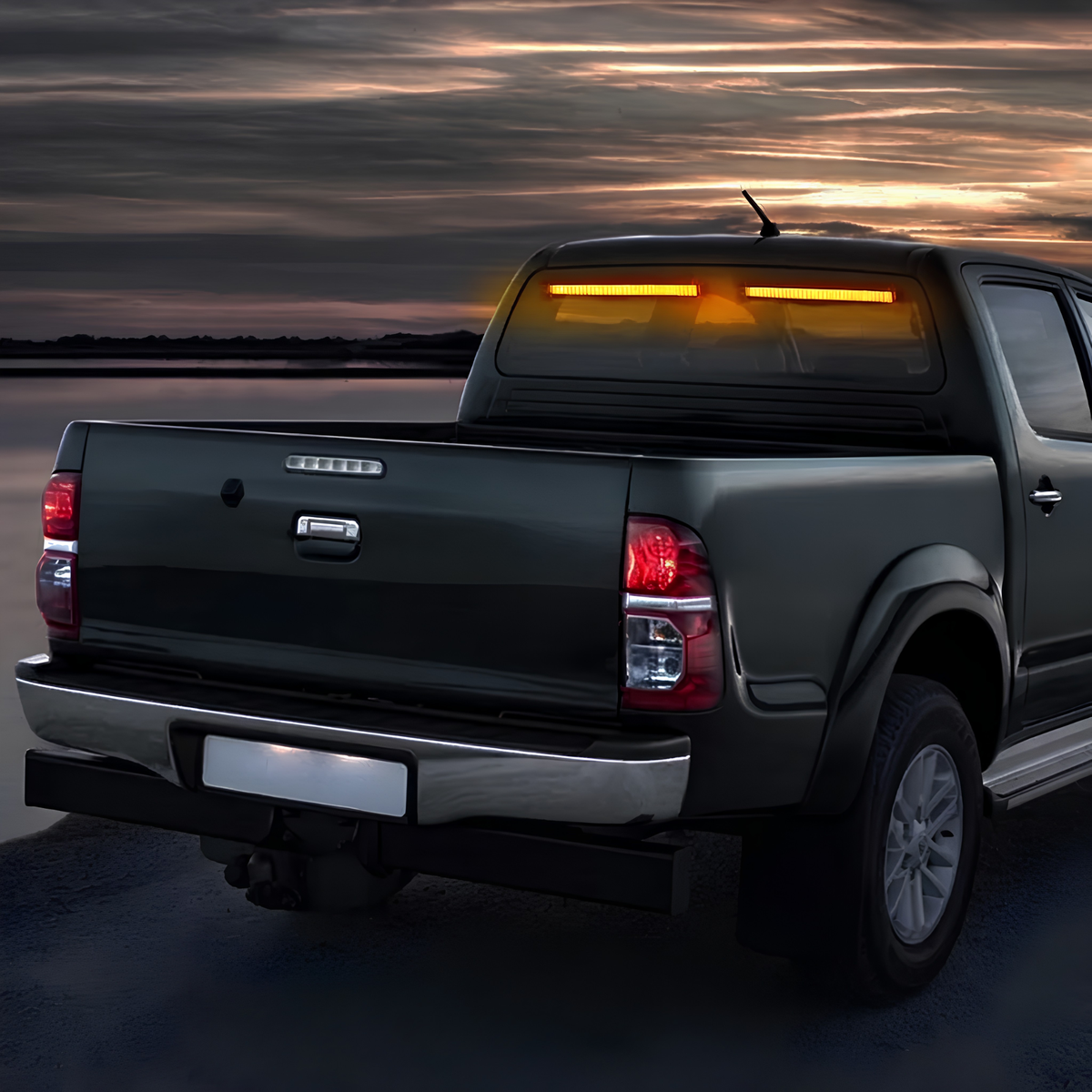 Amber LED Strobe Light Bar mounted inside the rear window of a black ute at dusk glowing amber