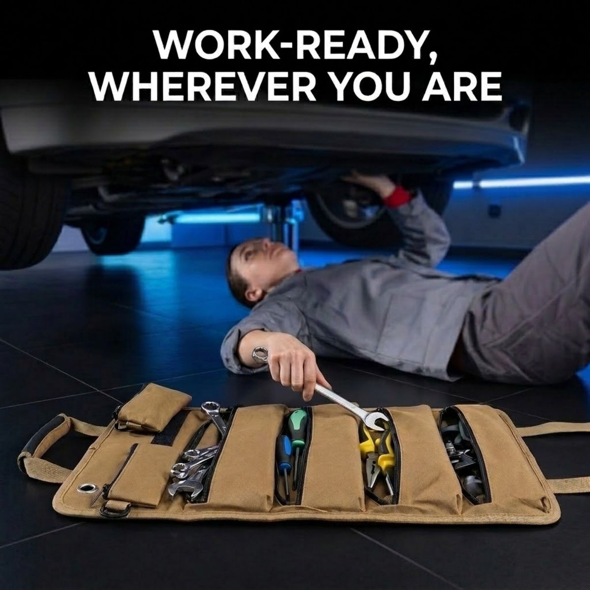 A tan canvas multi-tool roll filled with tools is laid open on a dark floor beneath a car, with a mechanic lying underneath the vehicle reaching for tools. Large white text at the top reads 'WORK-READY, WHEREVER YOU ARE'.