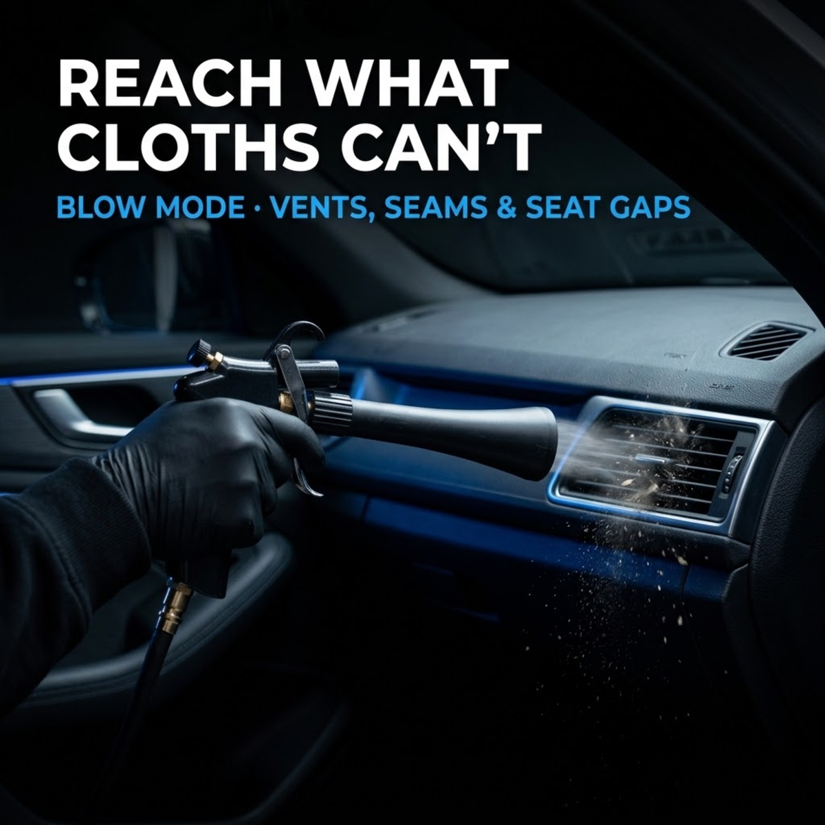 Gloved hand using the air detailing gun in blow mode to clear dust from a car dashboard air vent