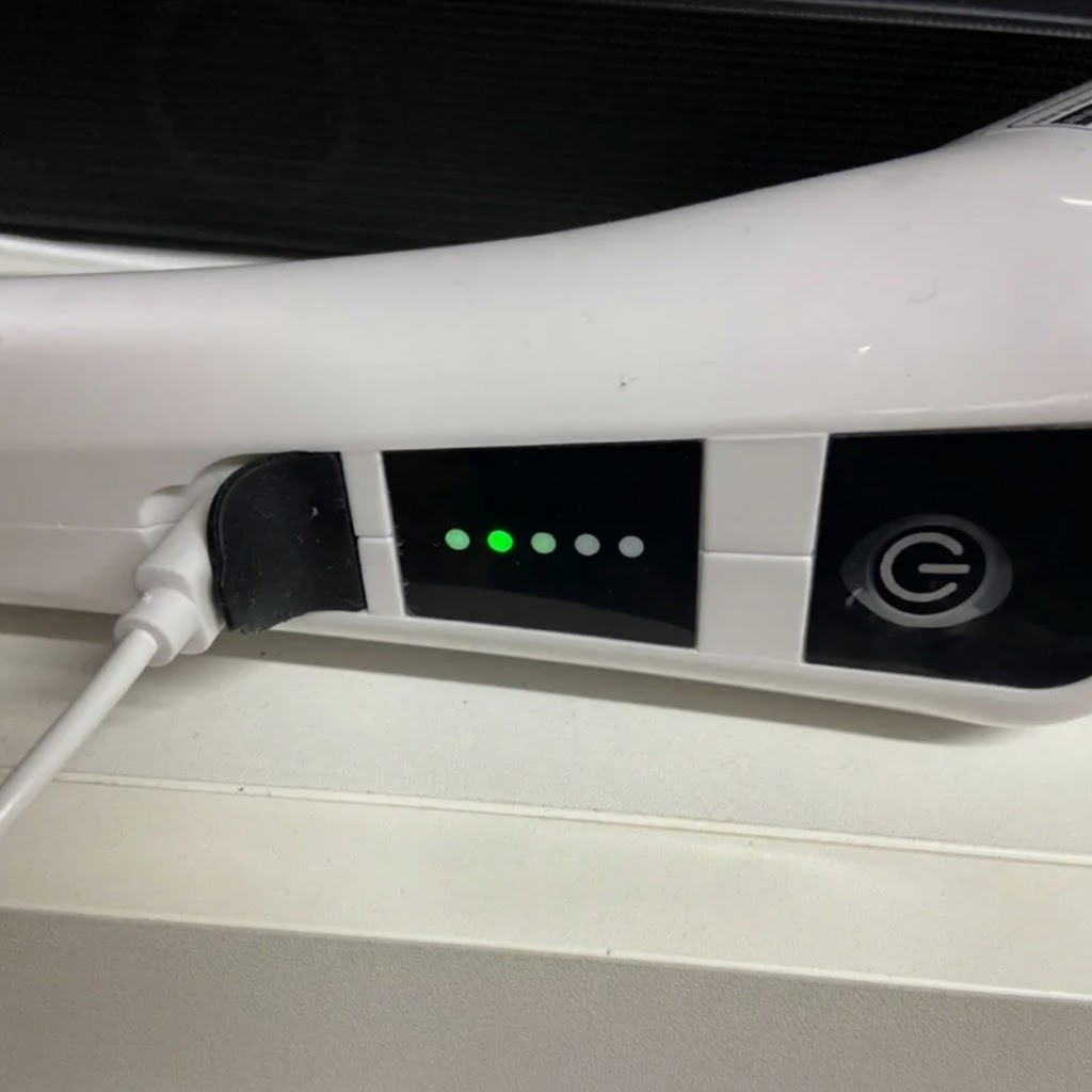 Cordless Power Spin Scrubber charging via cable with green battery level indicator lights