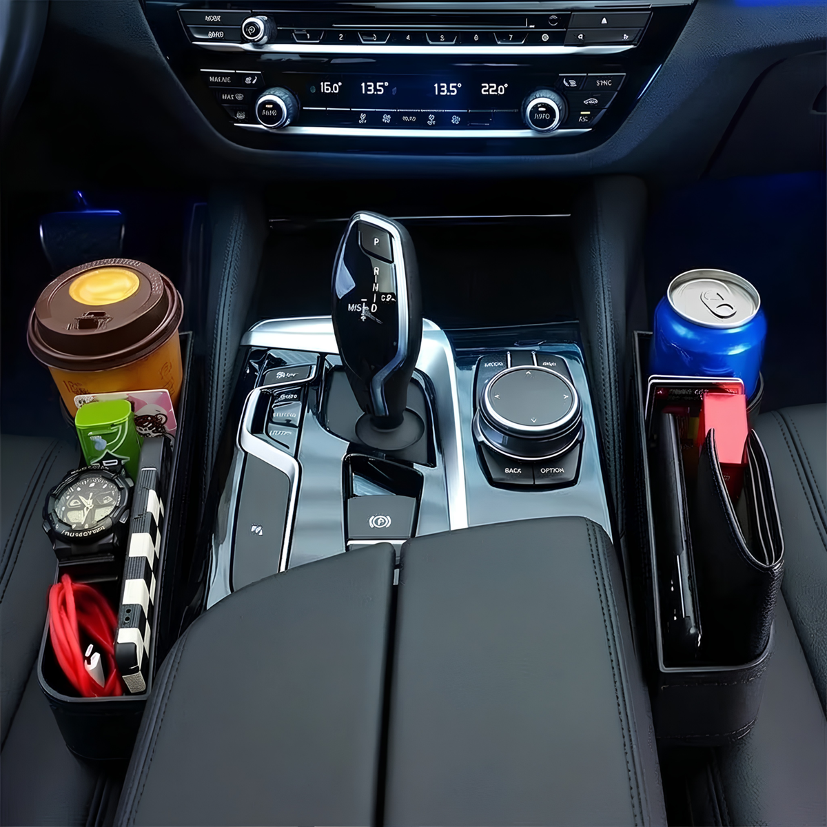 A black car center console organizer holding a coffee cup, watch, cable, wallet, and a blue soda can, installed in a car interior.