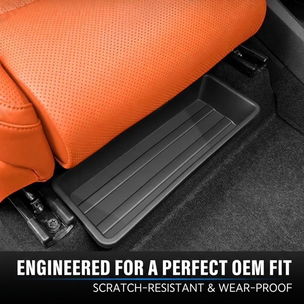 A black rectangular under-seat storage tray fitted into the gap beneath an orange perforated leather car seat, with carpet visible around it and text at the bottom reading 'ENGINEED FOR A PERFECT OEM FIT'.