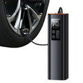 A black digital tire pressure gauge connected to a car wheel, shown on a clean white background. The gauge has a small LCD display showing PSI and BAR, with a black hose plugged into the wheel valve.