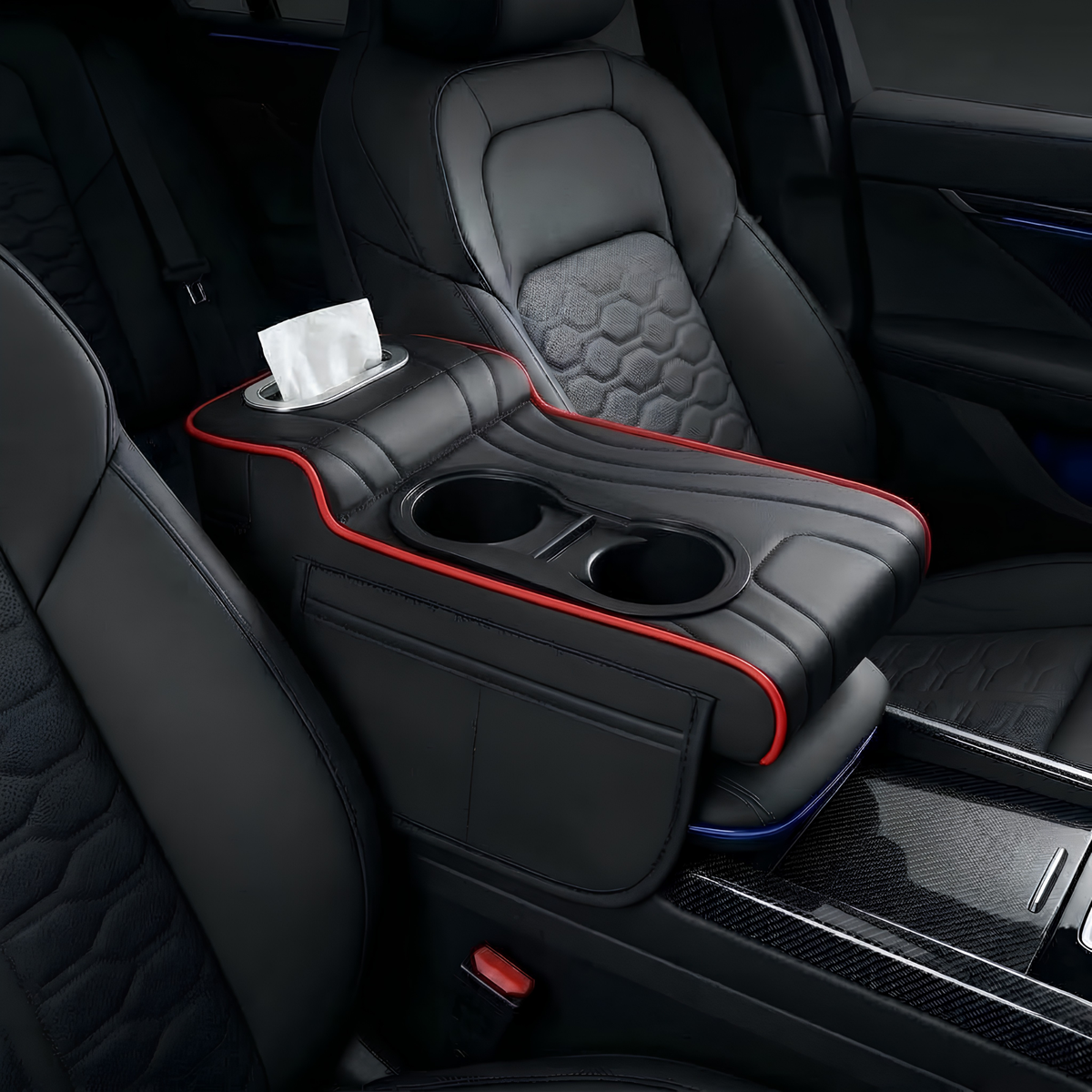 A black car center console armrest organizer with red piping trim, featuring two cup holders, a tissue dispenser slot, and a tissue box, shown installed between front seats in a car interior.