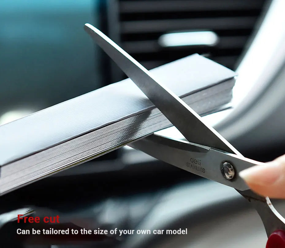 Scissors trimming the pleated film of a Retractable Windscreen Sunshade to fit the car's windscreen size