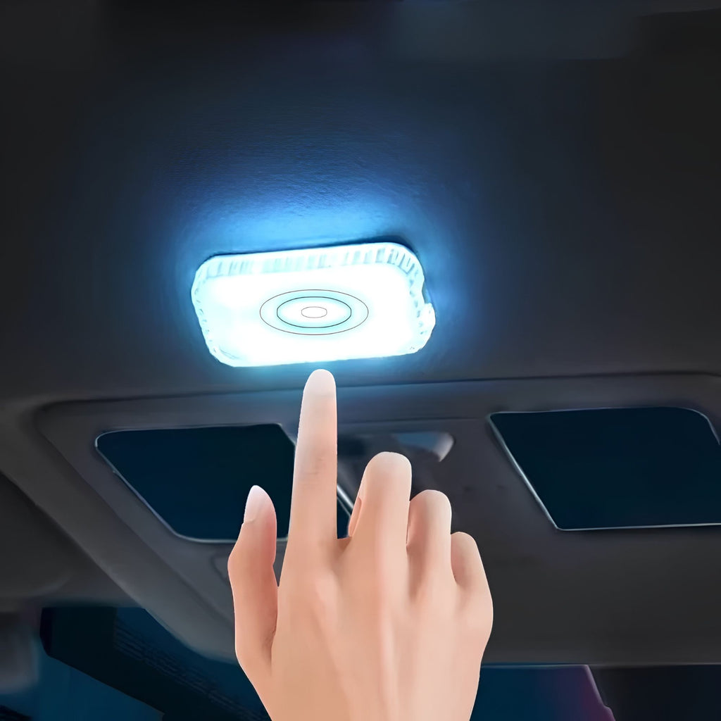 Finger touching a glowing white LED touch light mounted on a car ceiling roof panel above the sun visors
