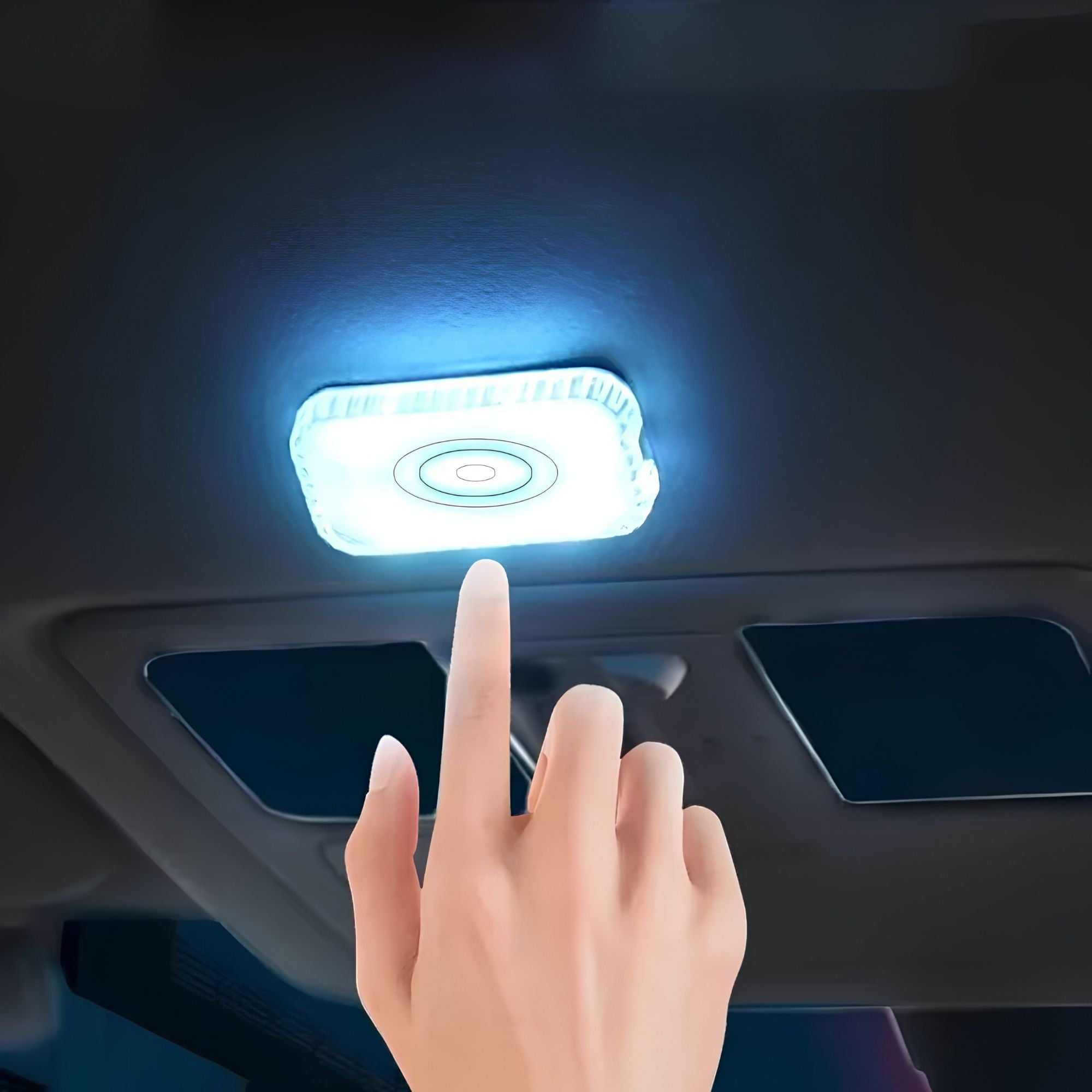 Finger touching a glowing white LED touch light mounted on a car ceiling roof panel above the sun visors