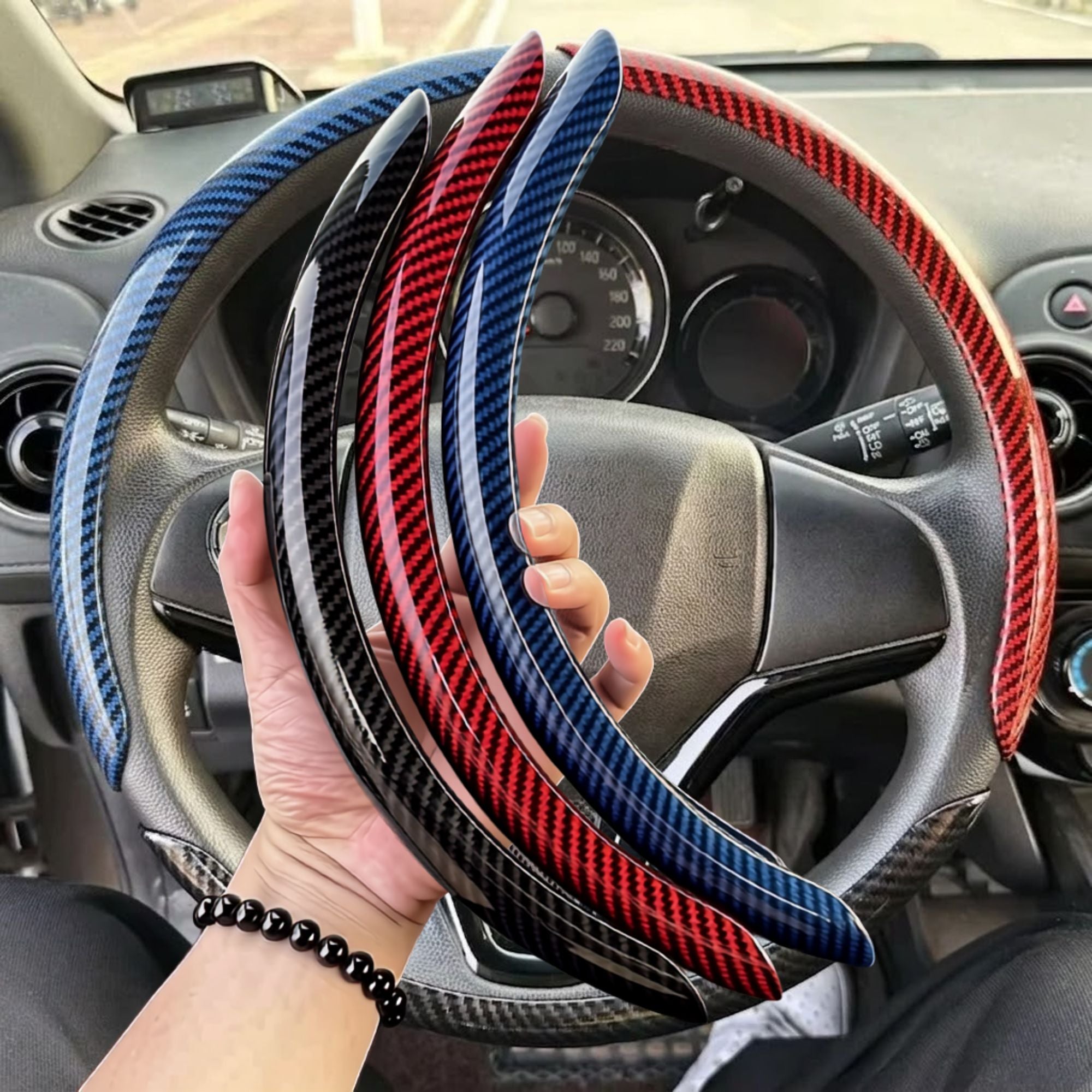 Hand holding black blue and red Carbon Fibre Wheel Cover colour options inside car