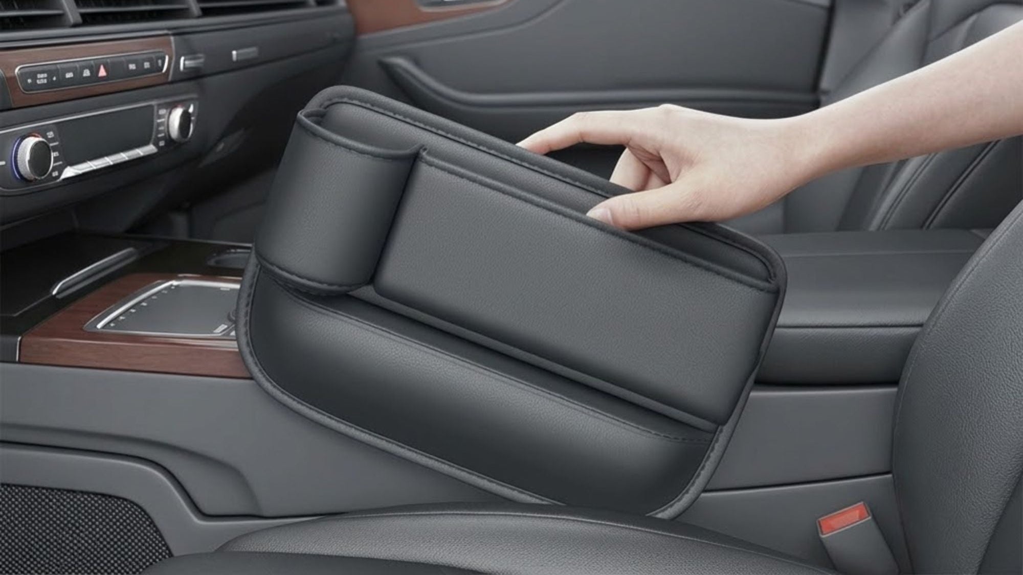 A hand holding a black car seat cushion inside a vehicle cabin, with text at the top explaining that bumps are stuck tightly without shifting and that it comes with a seam sponge strip between the seat and center console.