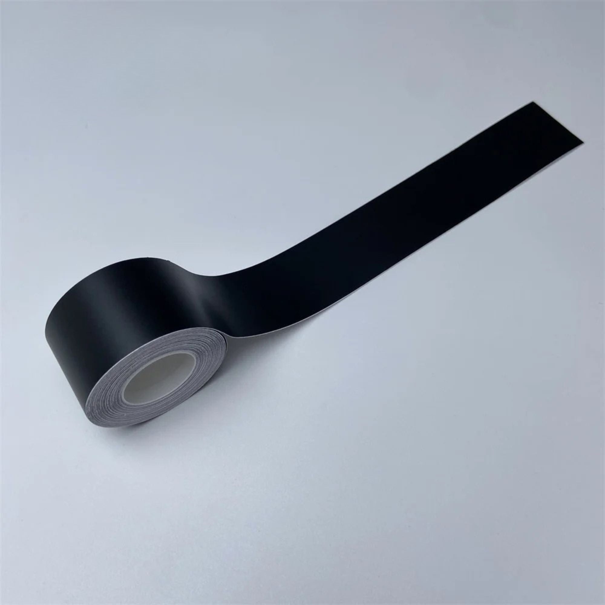Roll of Matte Black Trim Wrap vinyl film partially unrolled on a white background