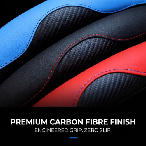 Close-up of a gaming chair seat showing black and blue faux leather panels with red stitching and a carbon-fibre-look textured center panel, plus text reading 'PREMIUM CARBON FIBRE FINISH ENGINEERED GRIP. ZERO SLIP.