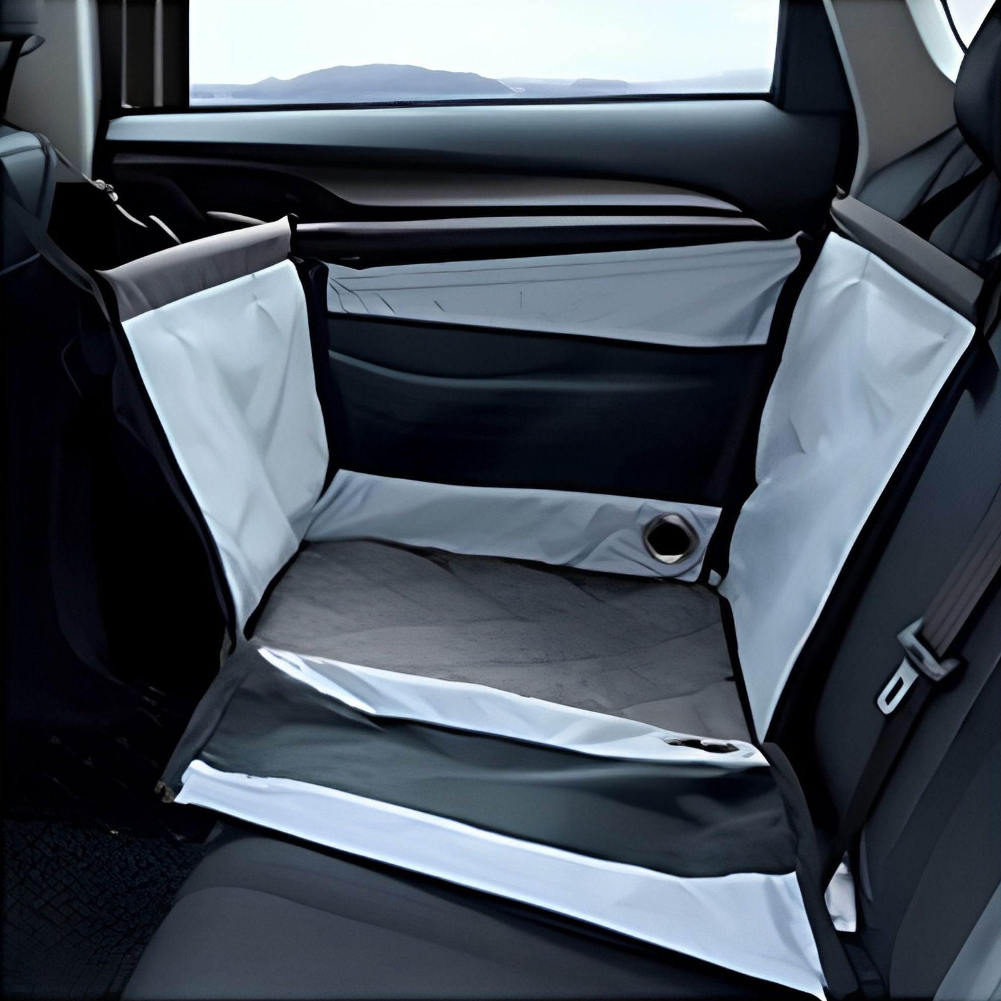 Empty grey portable pet car seat installed in a car back seat, view from inside showing padded base
