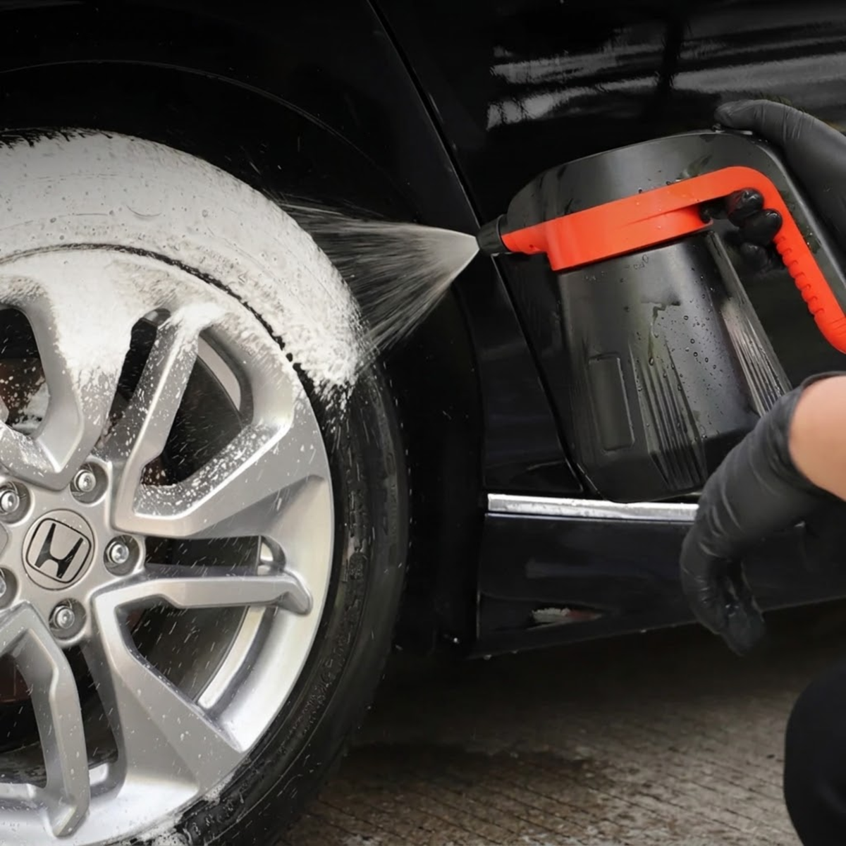 Gloved hand spraying foam onto a car wheel and tyre with the Pro Dual-Nozzle Foam Sprayer