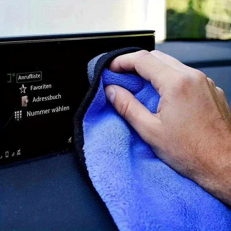 Hand wiping a car's touchscreen infotainment display with a soft microfibre cloth