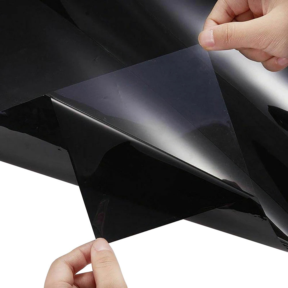 Hands peeling the backing from a sheet of Windscreen Sun Visor Strip dark tinted film