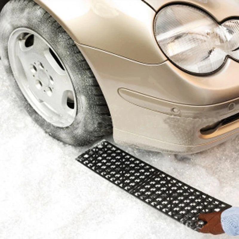 Emergency tyre traction mat deployed under car tyre stuck in snow on the road