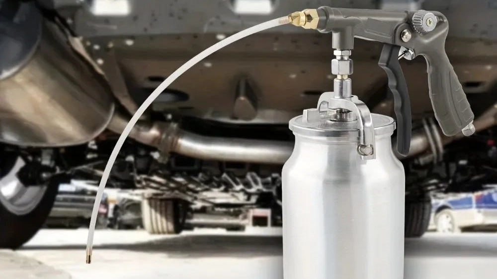 A metal spray paint gun with an extension hose is shown over a blurred car undercarriage, with text and two circular inset close-ups explaining hose use. This is not a clean standalone product shot because a real environment and explanatory text are present, so subject_type is Lifestyle rather than Product/Packaging.