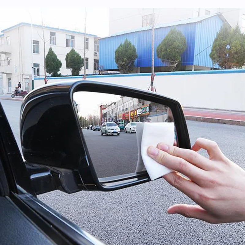 Hand wiping a car side mirror with a cloth after applying Hydrophobic Glass Shield coating