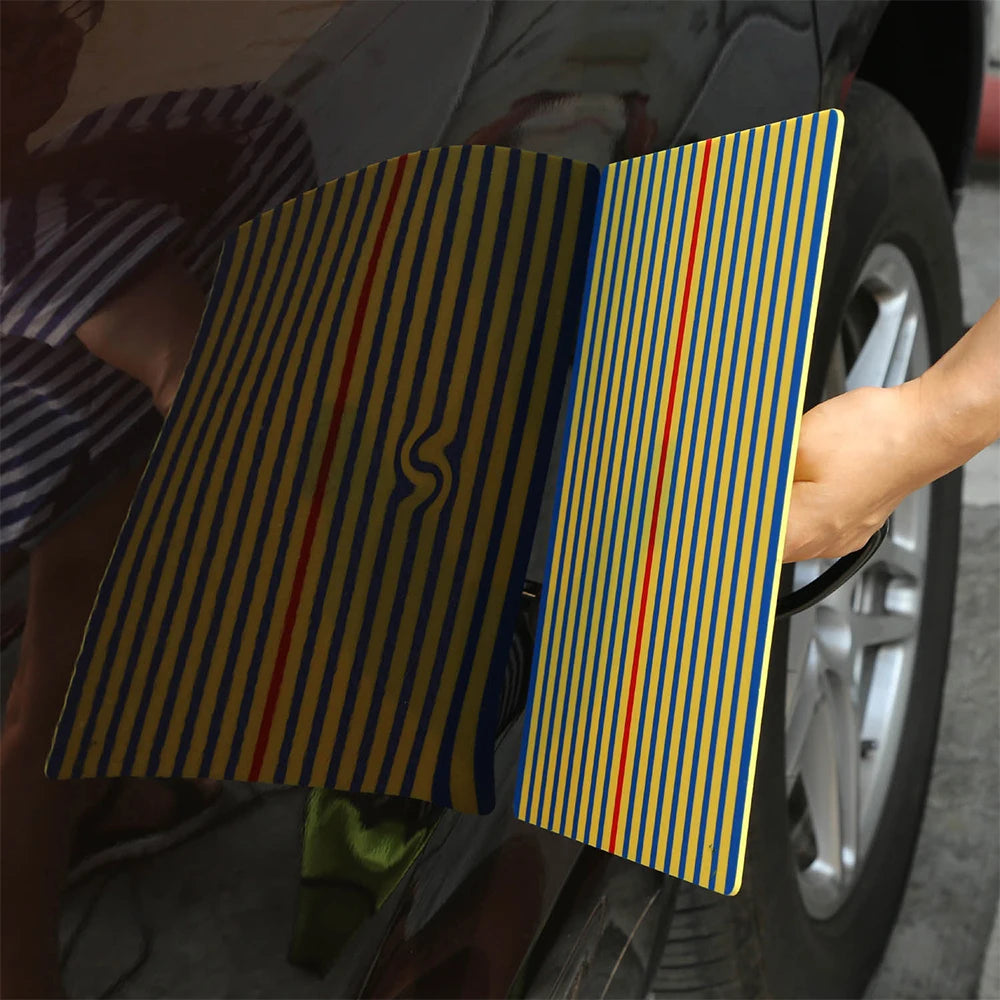 Hand holding the PDR Dent Repair Kit's line board reflector against a car panel to locate a hidden dent