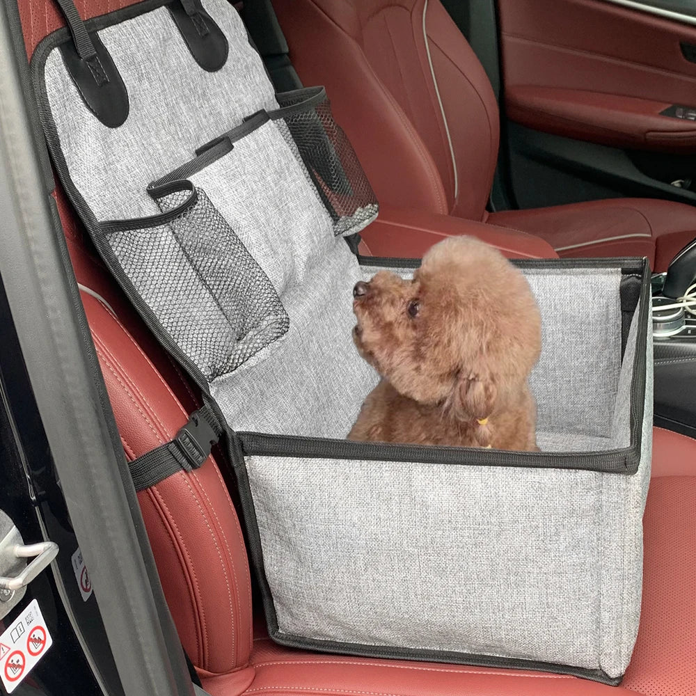 Small dog sitting comfortably inside a foldable car booster seat installed on a vehicle front seat, showcasing the pet travel carrier in use.