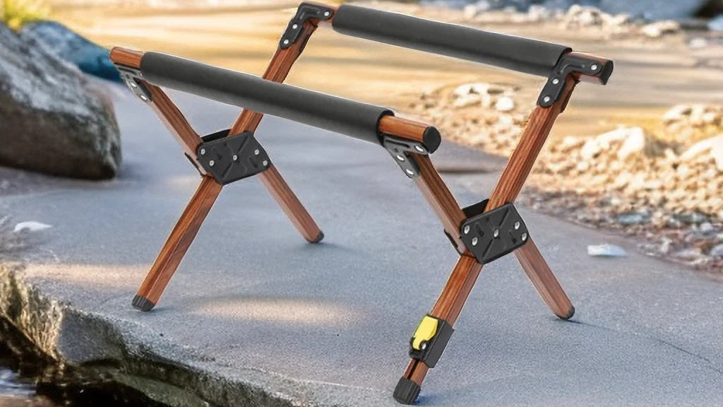 Portable camping stool with wooden legs and black adjustable arms on a natural outdoor setting.
