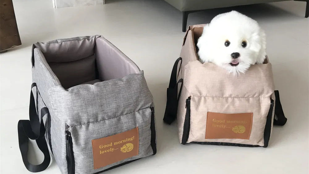 Two pet carriers, one gray and one beige, with a white dog inside the beige carrier on a light-colored floor.