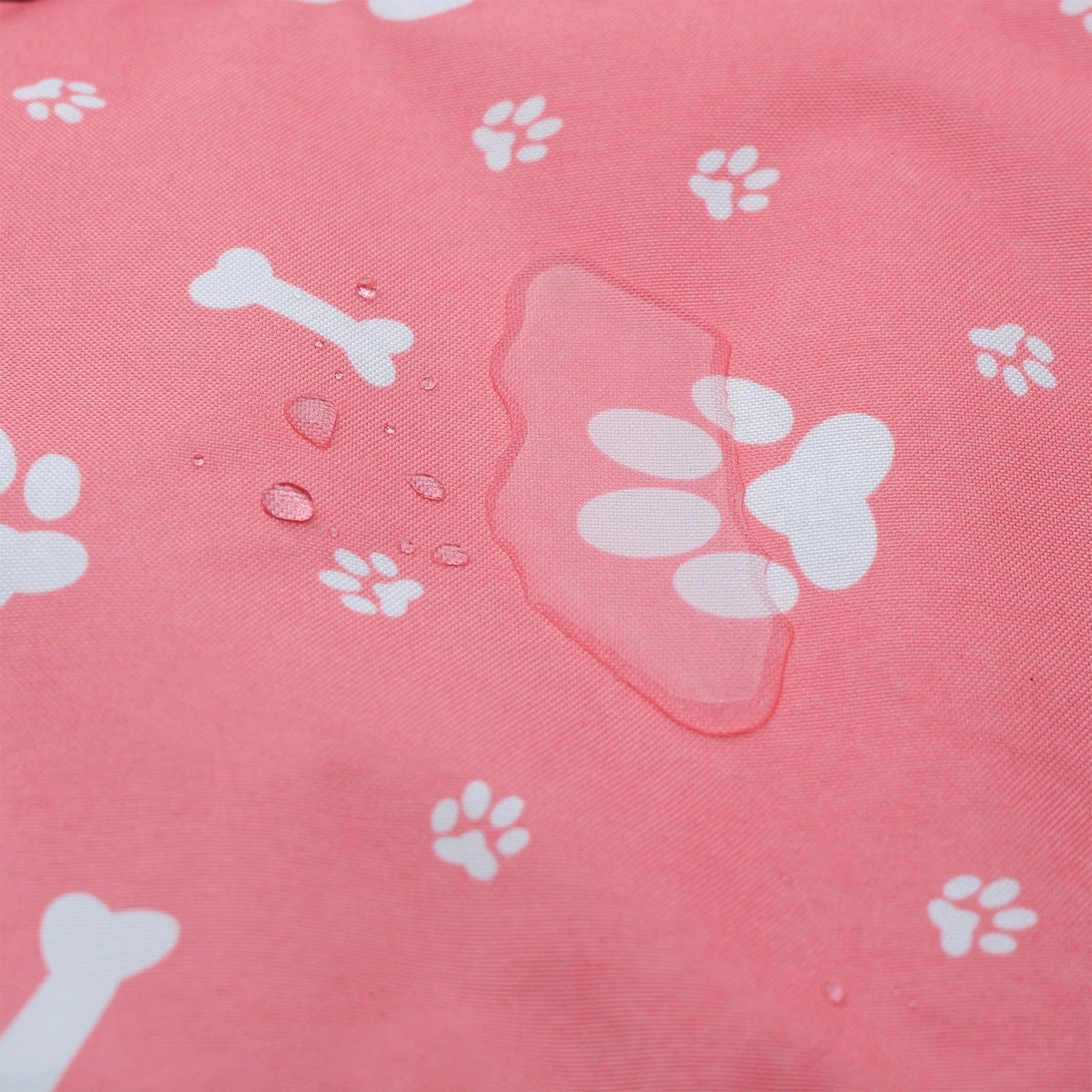 Close-up of waterproof pink paw print fabric showing water droplets beading on the surface