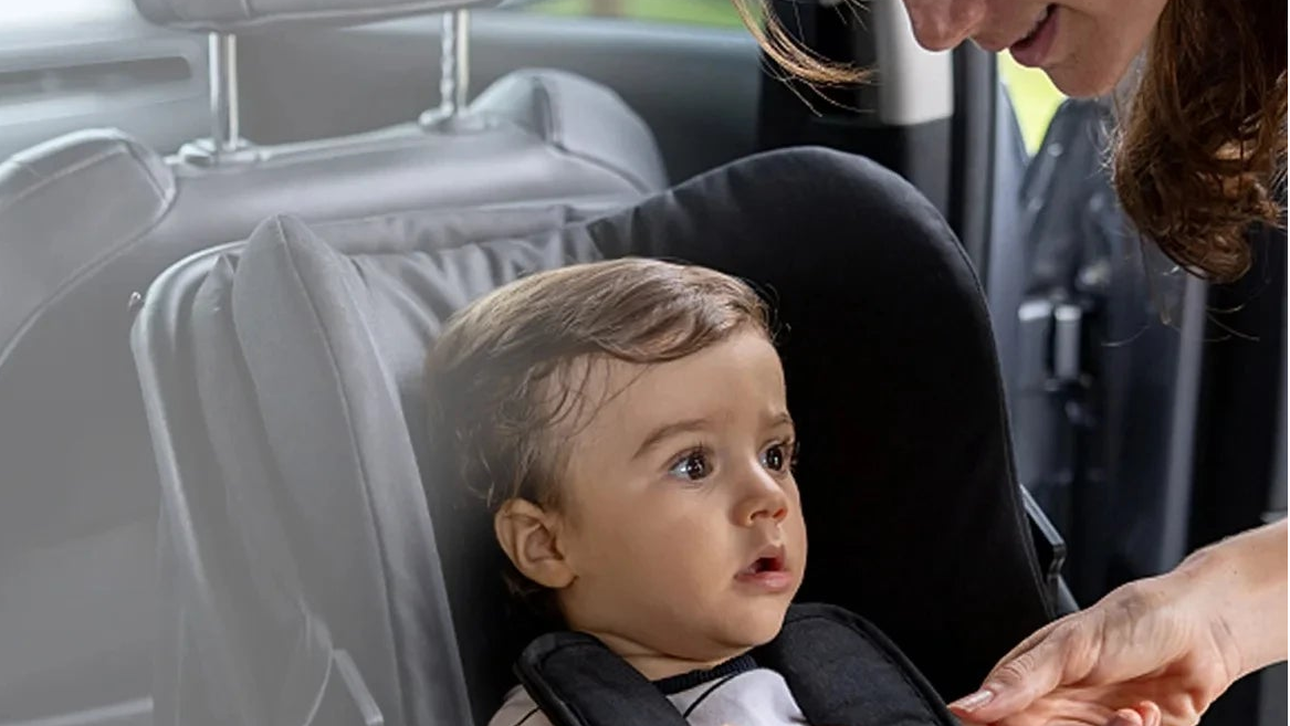 Woman adjusting a child in a car seat with a monitor attached, surrounded by step-by-step icons on a dark overlay.