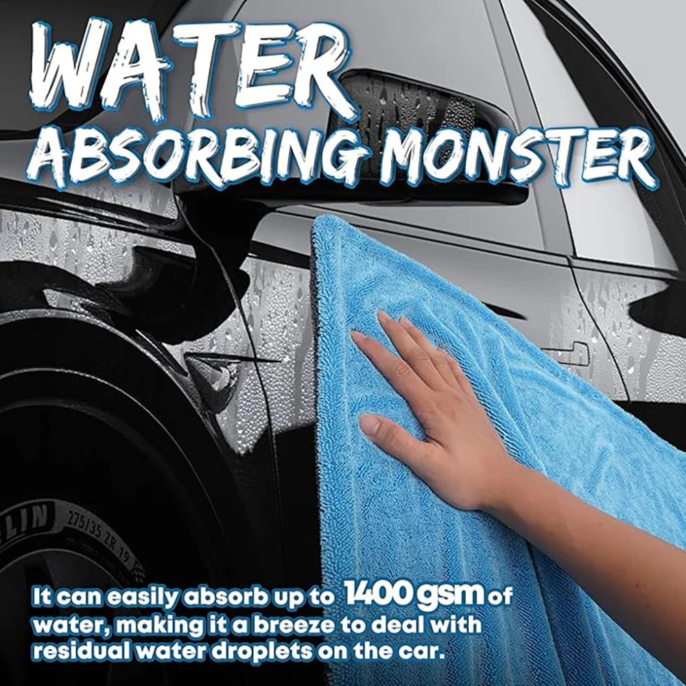 Hand using a blue Microfiber Car Drying Towel to wipe water droplets from a black car's exterior panel and side mirror.