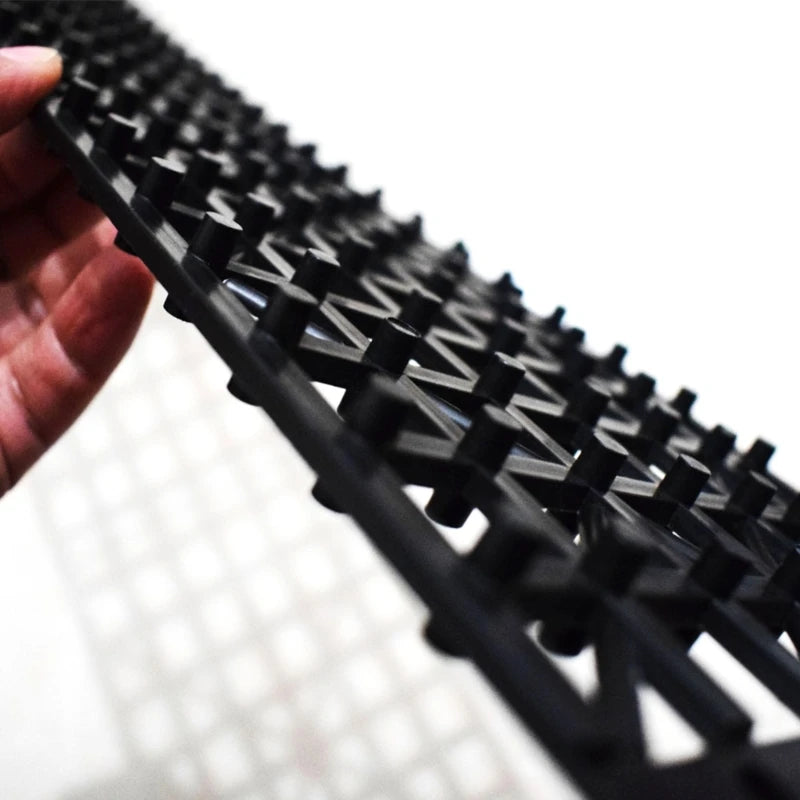 Close up of hand holding emergency tyre traction mat showing V-shaped traction cleats