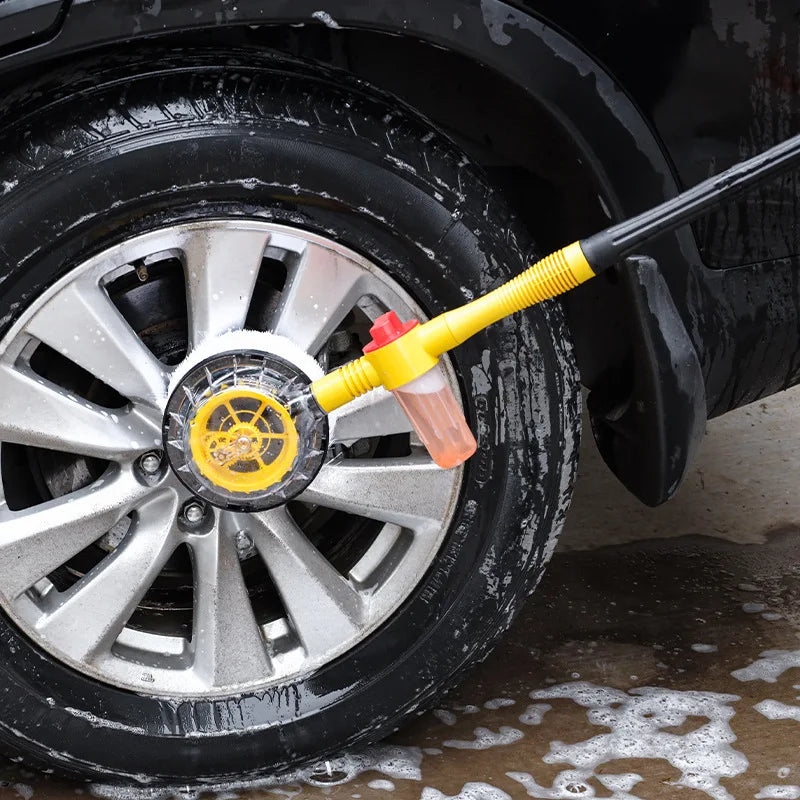 Rotating foam wash mop scrubbing thick suds onto a car alloy wheel and tyre