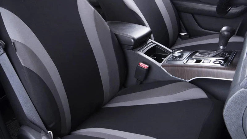 Black and gray car seat covers installed on the front seats of a vehicle interior, shown with the dashboard, center console, and windows visible.