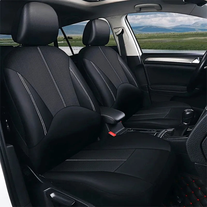 Universal Seat Cover Set installed in black leather on car front seats with headrests, viewed through open door with grassy landscape background