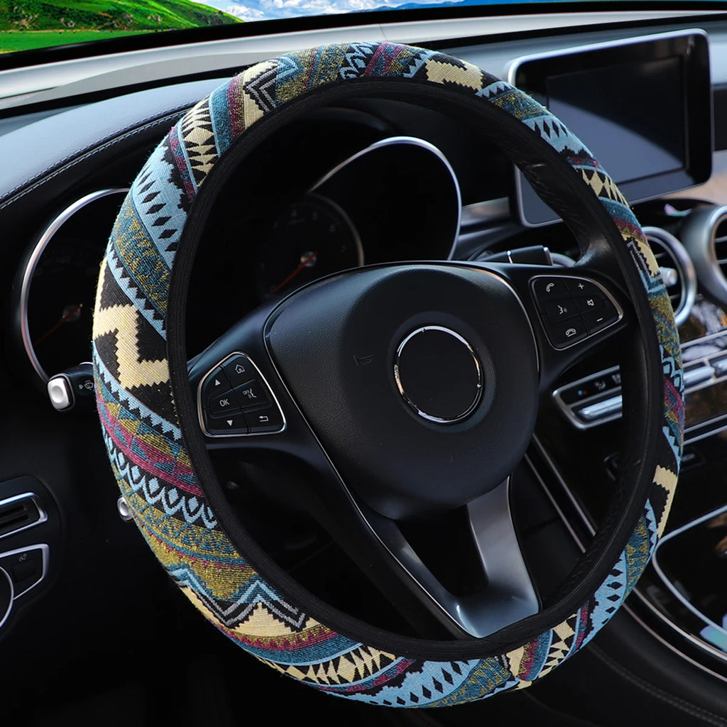 Blue, red and beige tribal pattern linen steering wheel cover fitted on a car steering wheel with multifunction buttons visible