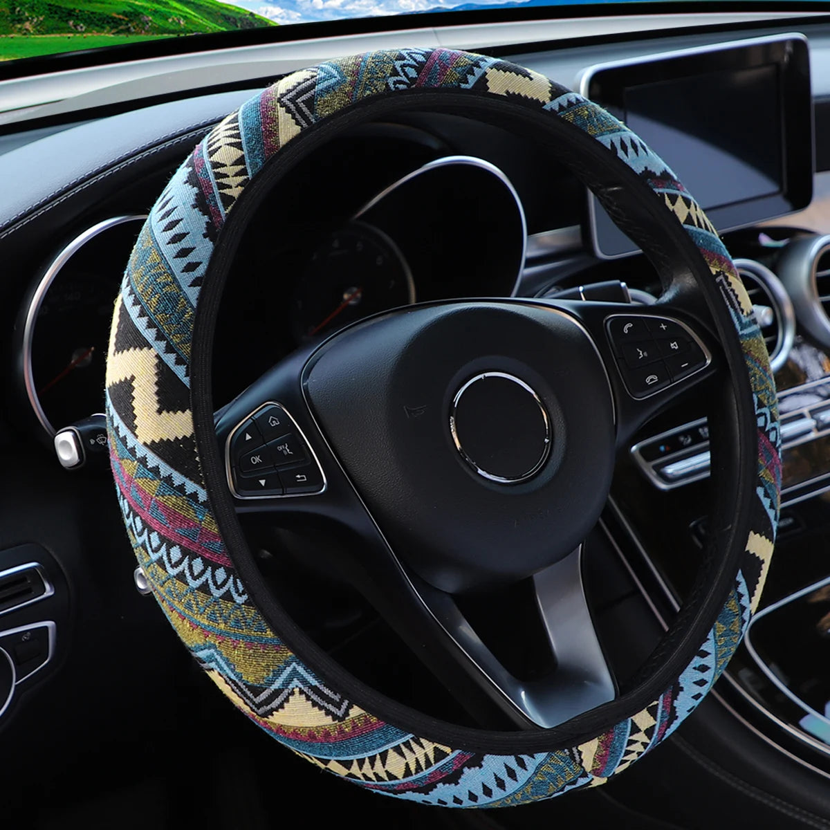 Blue, red and beige tribal pattern linen steering wheel cover fitted on a car steering wheel with multifunction buttons visible