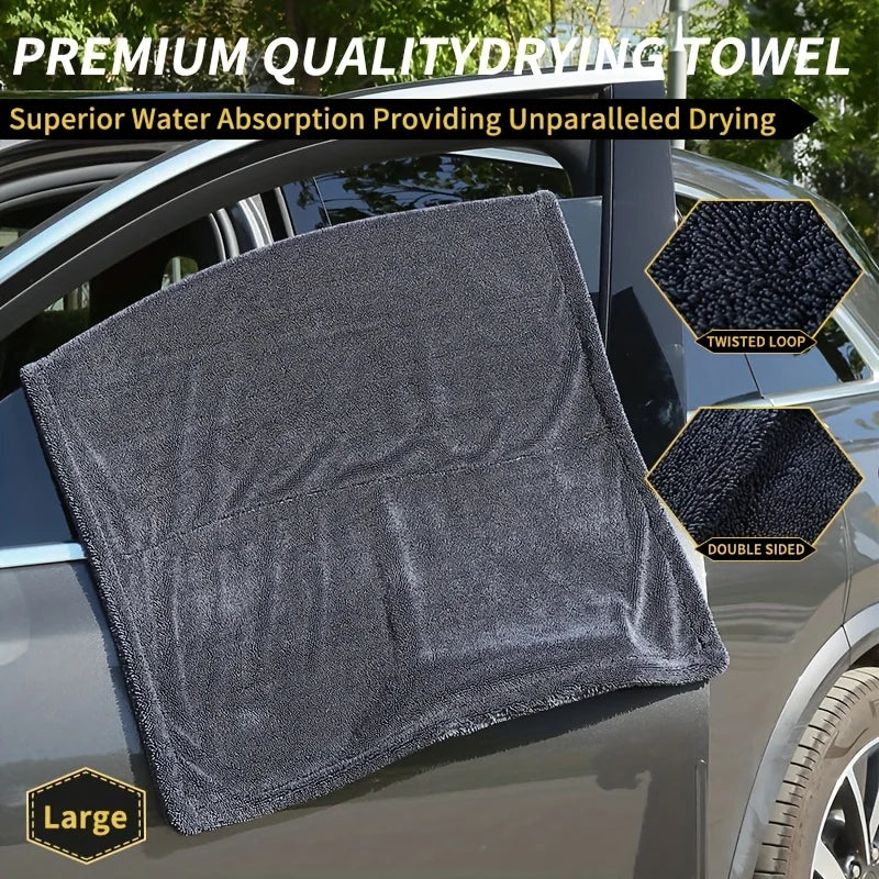 Two hands using the XXL Microfiber Drying Towel to dry a wet car rear windscreen area, with a thick fabric badge