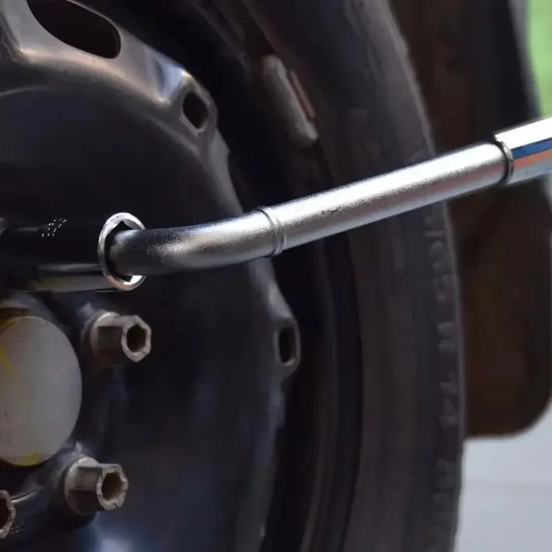 Close-up of the telescoping lug wrench tip inserted into a lug nut on a dark alloy wheel