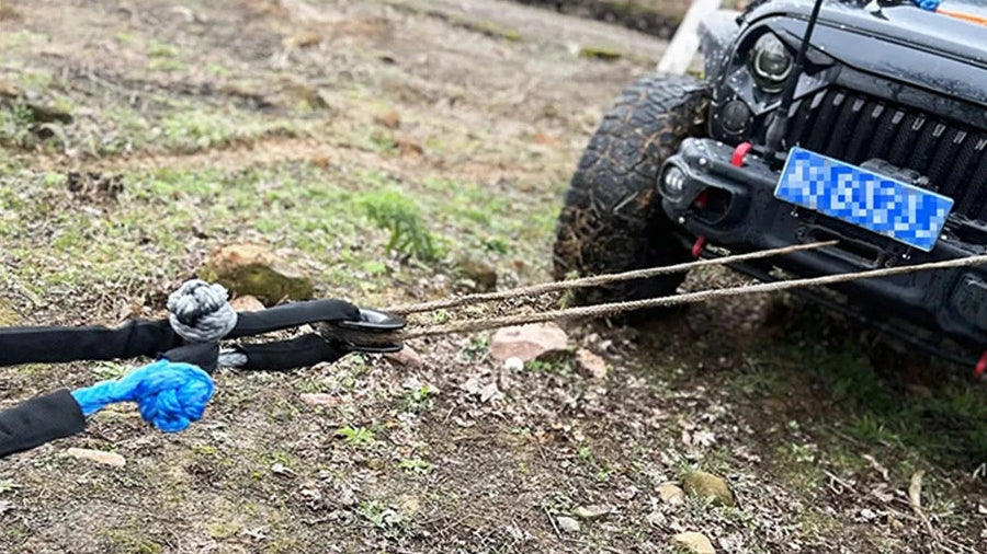 Tow strap being used to pull a vehicle on a dirt road, with close-up of the strap's clasp.