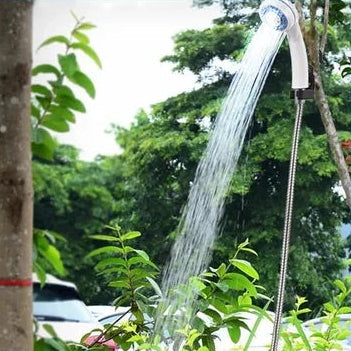 Rechargeable Camp Shower Kit spraying water outdoors with the shower head clipped to a tree