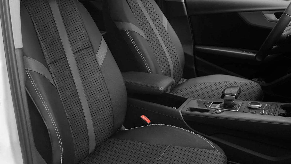 Black car seat covers installed on the front seats of a vehicle interior, featuring a textured pattern and contrast stitching.