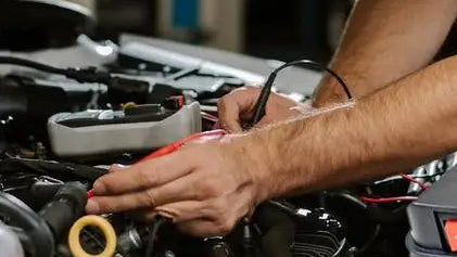 Man working on a car with a car start power converter in the foreground.