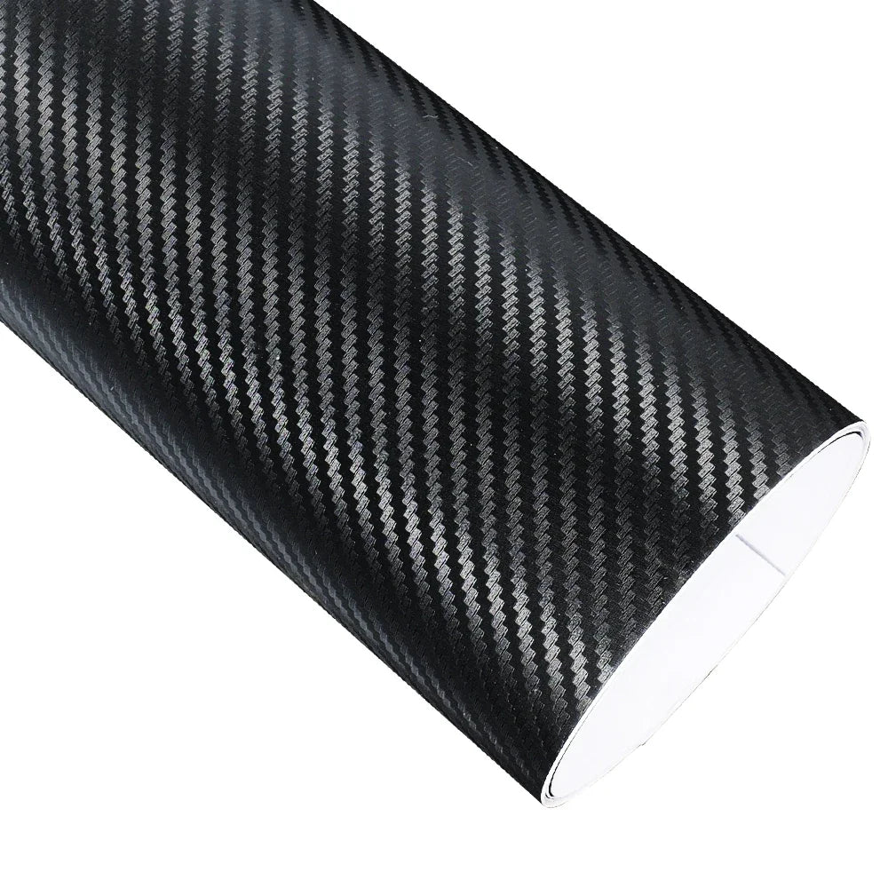 Roll of black carbon fibre vinyl wrap film unrolled on a white background showing the glossy diagonal weave pattern