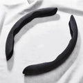 Suede Car Steering Wheel Cover in black, two-piece non-slip grip protector on a light fabric background