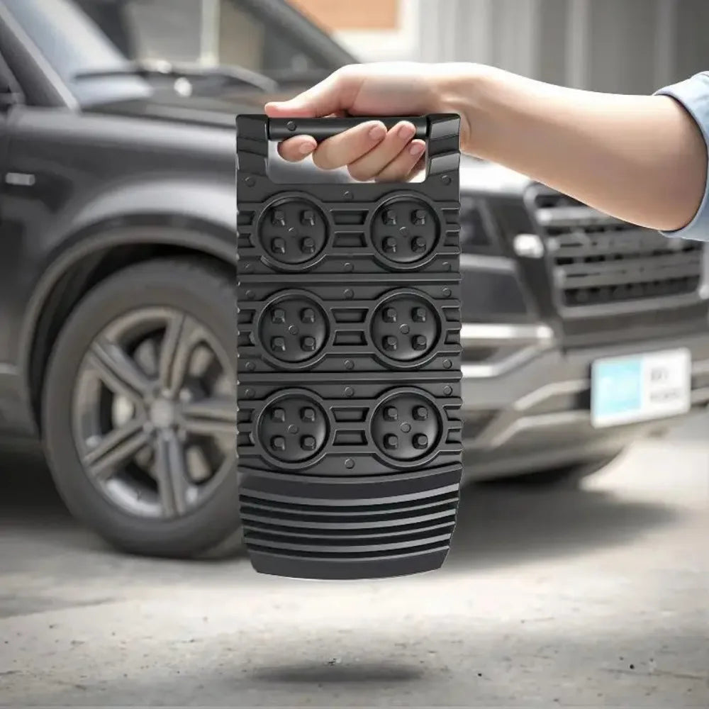 Hand holding a Compact Tyre Traction Mat by its handle in front of a black SUV