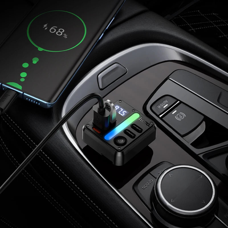 Dual-Port Bluetooth FM Transmitter plugged into a car centre console charging a smartphone showing 68 per cent battery