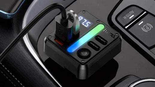 Car dashboard with a wireless phone charger and digital display showing battery levels.