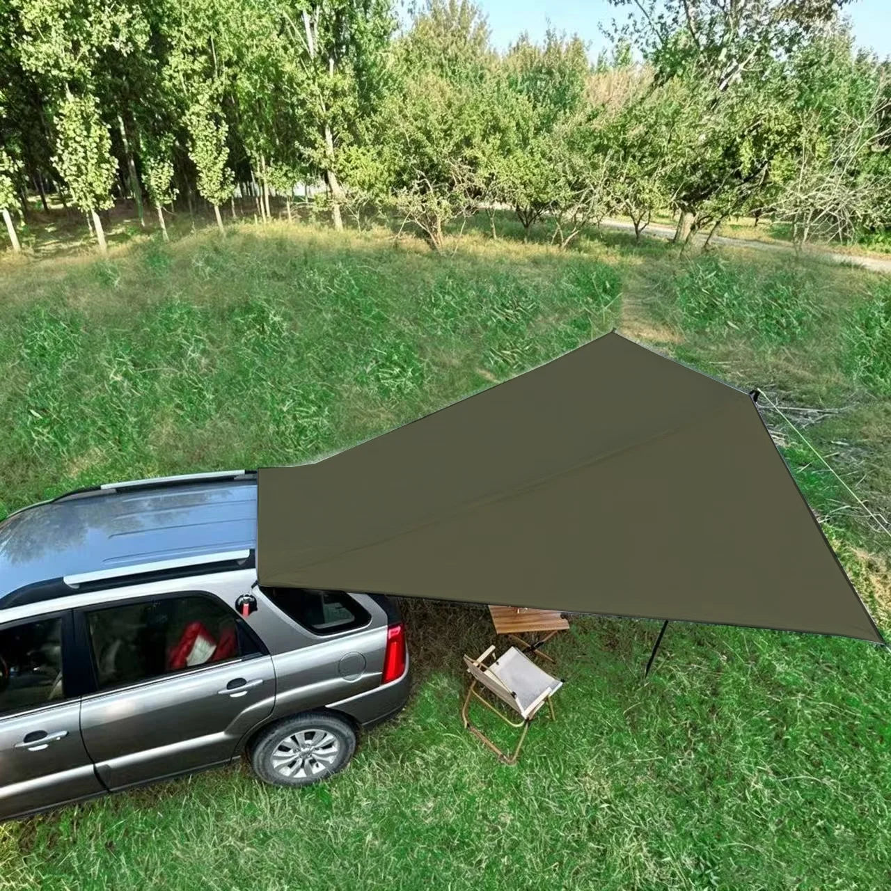 Expedition Side Sunshade shading a camp table and chair beside a silver SUV parked in a grassy park