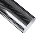 Roll of black 5D carbon fibre vinyl wrap film unrolled diagonally on a white background showing the glossy woven texture