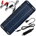 Solar battery trickle charger panel with red and black alligator clips, USB adapter cable and cigarette lighter plug laid flat on a white background