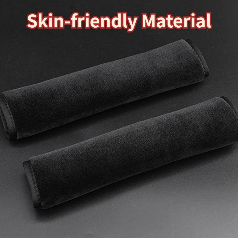 Two black seat belt shoulder pads laid on a dark background with skin-friendly material text overlay